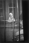 853933 Afbeelding van een jonge vrouw op straat te Utrecht, gezien door een vitrage.